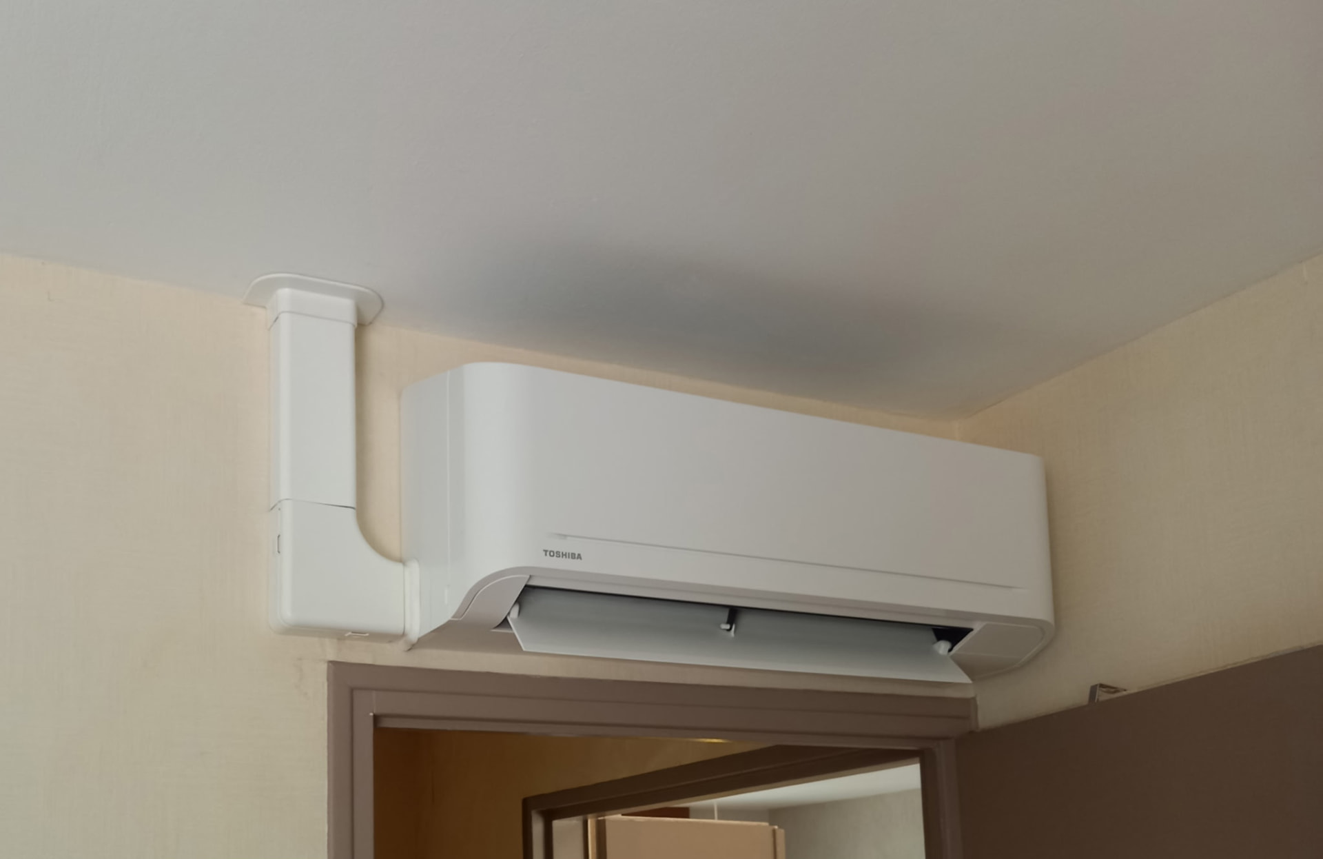 Unité intérieure de climatisation murale Toshiba installée au-dessus d'une porte